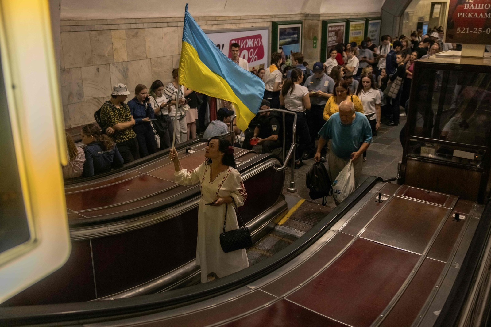 Uma mulher agita uma bandeira ucraniana enquanto as pessoas se abrigam na estação de metrô Khreshchatyk durante um alarme de ataque aéreo no Dia da Independência da Ucrânia, em Kiev — Foto: Roman Pilipey / AFP