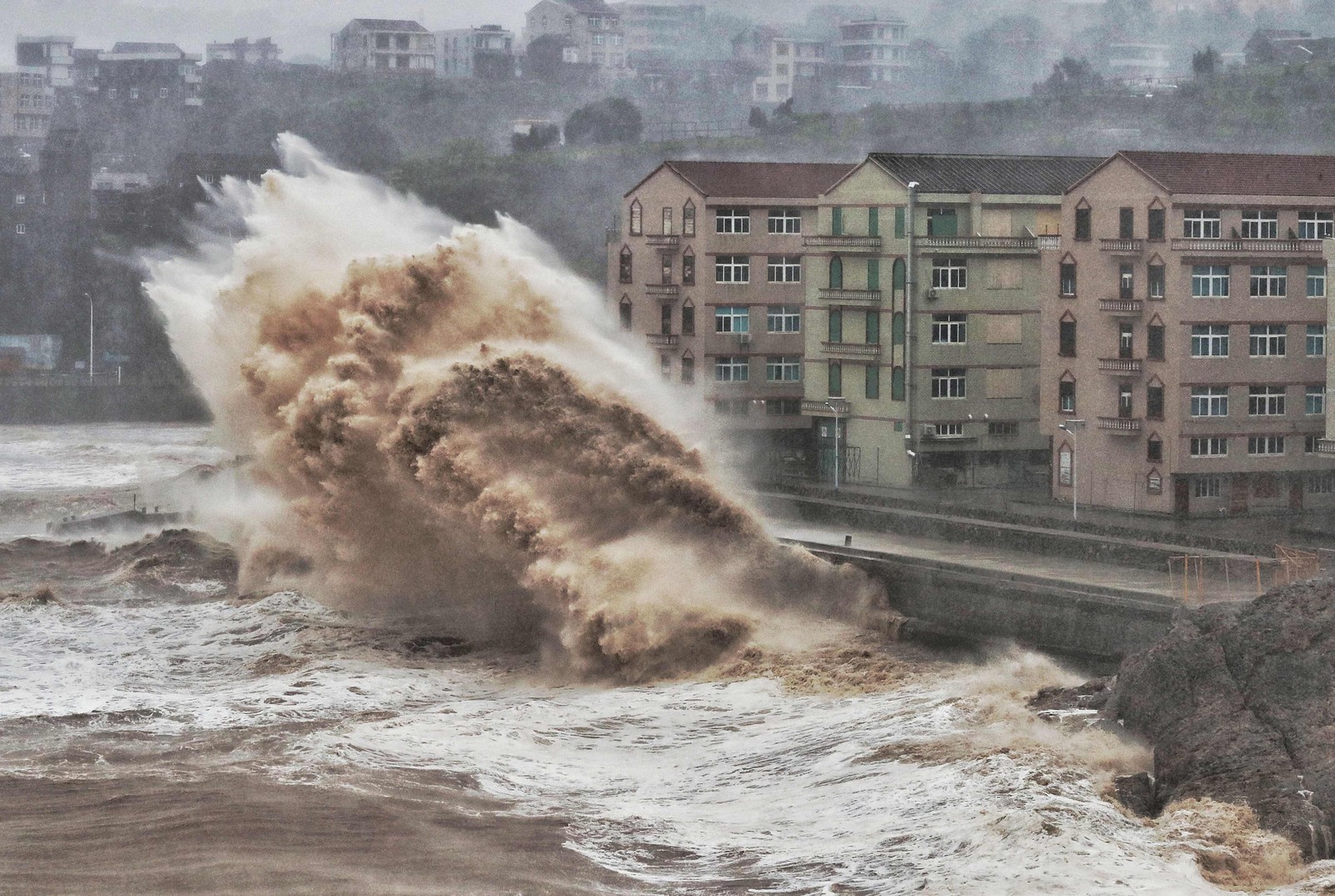 Ondas atingem um paredão em frente a edifícios em Taizhou, província de Zhejiang, leste da China. Os mesmos oceanos que nutriram a evolução humana estão prontos para desencadear a miséria em escala global alerta um projeto de relatório da ONUAFP