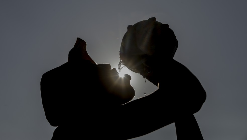 Antes das 8h, na praia do Leme, o barraqueiro Gabriel Oliveira bebe água de coco antes de um domingo de trabalho sob calor intenso — Foto: Gabriel de Paiva/ Agência O Globo