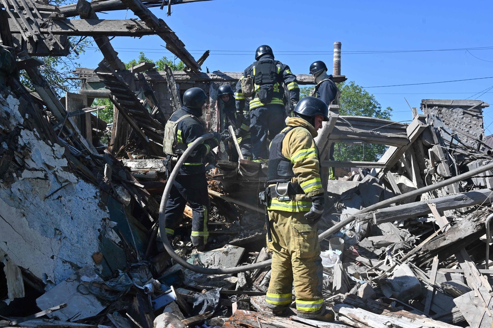 Bombeiros apagaram incêndio em uma casa particular destruída após a explosão de uma bomba aérea guiada em Kharkiv — Foto: SERGEY BOBOK/AFP