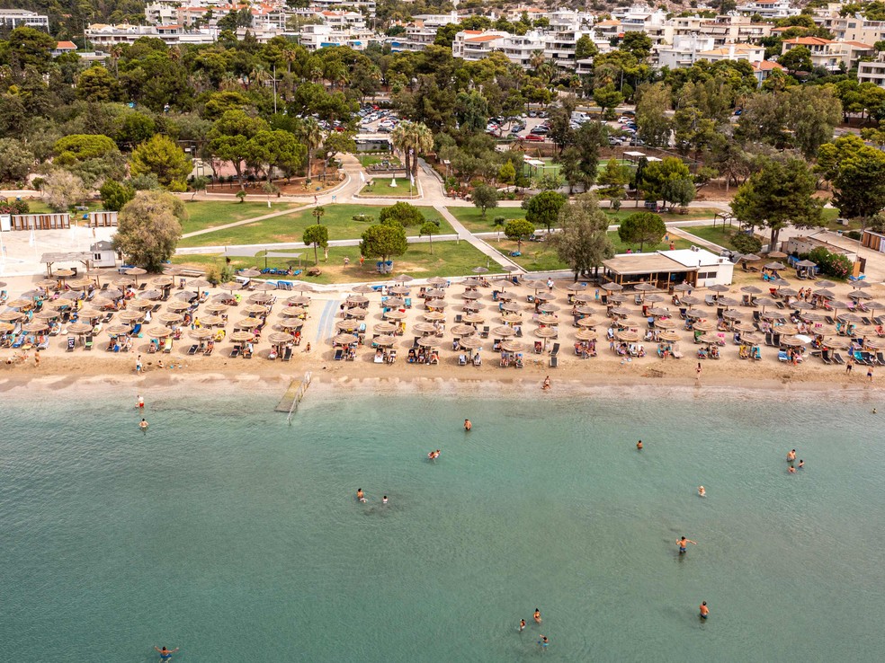 Banhistas tentam um espaço na areia tomada por barracas na praia de Oceanis, em Vouliagmeni, a 25km de Atenas, na Grécia — Foto: Spyros Bakalis / AFP