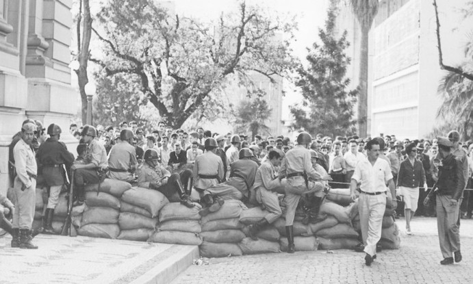 No Rio Grande do Sul, o governador Leonel Brizola, também do PTB, rebela-se, com apoio da população, contra a decisão dos militares. Brizola ameaça ir à guerra civil caso Jango não tomasse posse. Nesta foto, populares observam soldados que montaram barricada em Porto Alegre, no Rio Grande do Sul, durante o período da Campanha da Legalidade