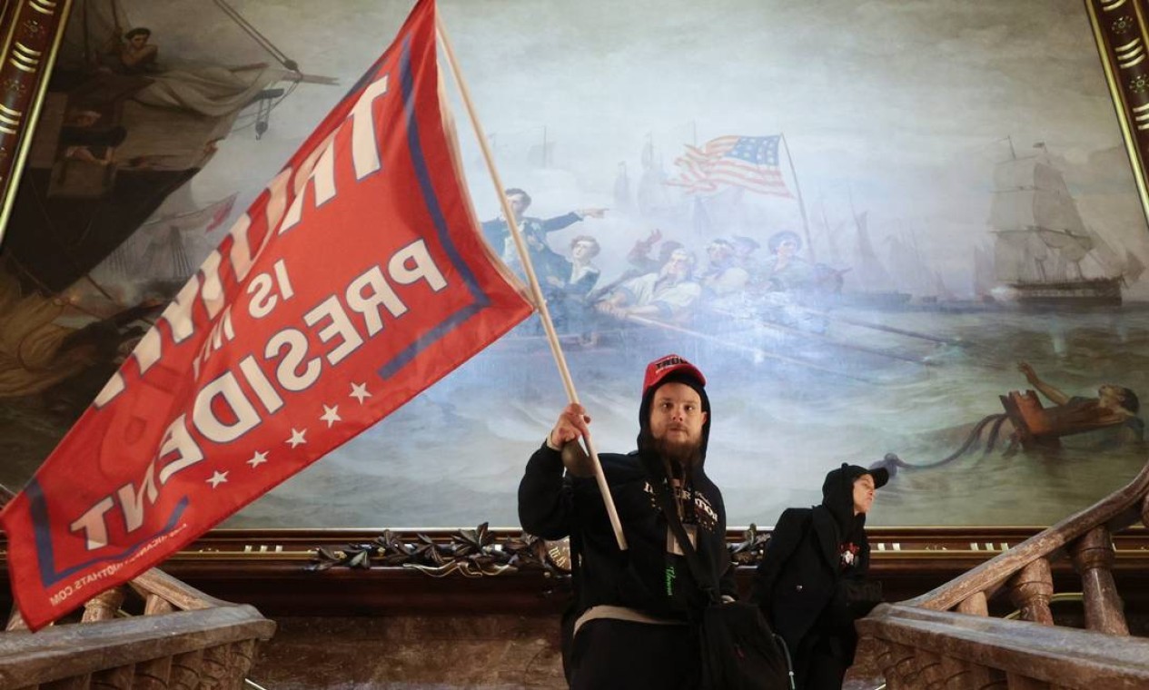 Um manifestante segura uma bandeira de apoio ao presidente Trump dentro do Capitólio dos EUA, perto da Câmara do Senado  — Foto: WIN MCNAMEE / AFP