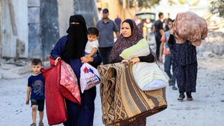 Mulheres palestinas caminham com crianças e pertences enquanto fogem de uma área após ataque aéreo israelense em Rafah, no sul da Faixa de Gaza — Foto: SAID KHATIB/AFP