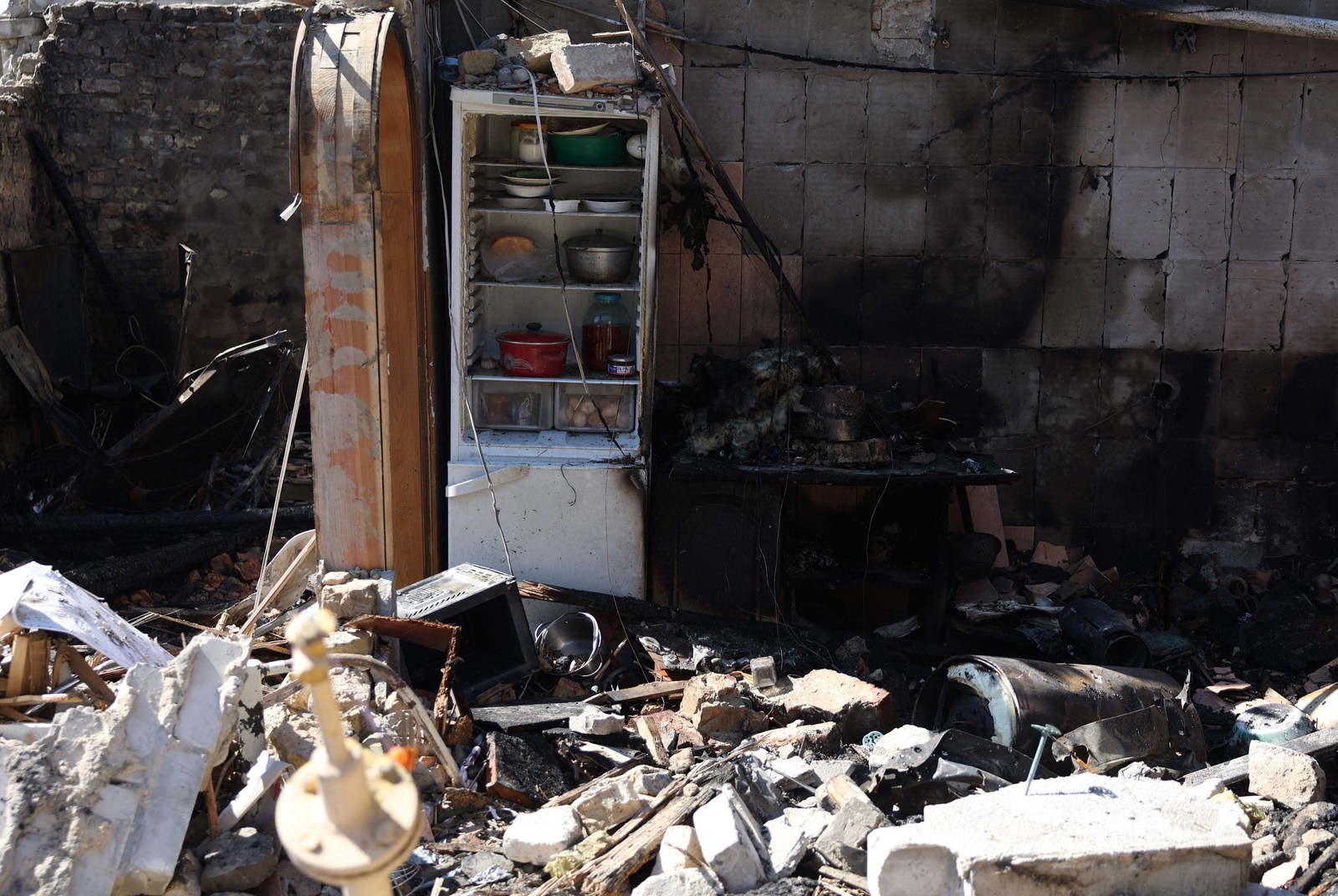 Moradores locais examinam uma casa particular destruída por um ataque de mísseis na vila de Krasylivka, região de Kiev, em 8 de maio de 2024, em meio à invasão russa na Ucrânia. — Foto: Anatolii STEPANOV/AFP