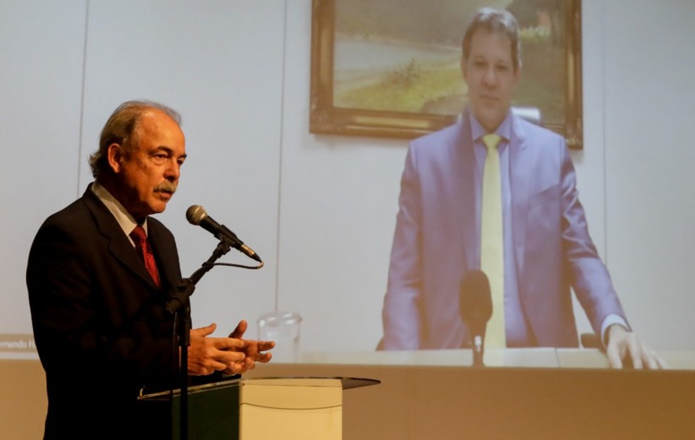 Mercadante disse que, sem parcelamento, BNDES terá que cortar financiamentos para governos estaduais e para produtores agrícolas; segundo o executivo, Haddad (no telão) apoia pedido do banco — Foto: Gabriel de Paiva/Agência O Globo