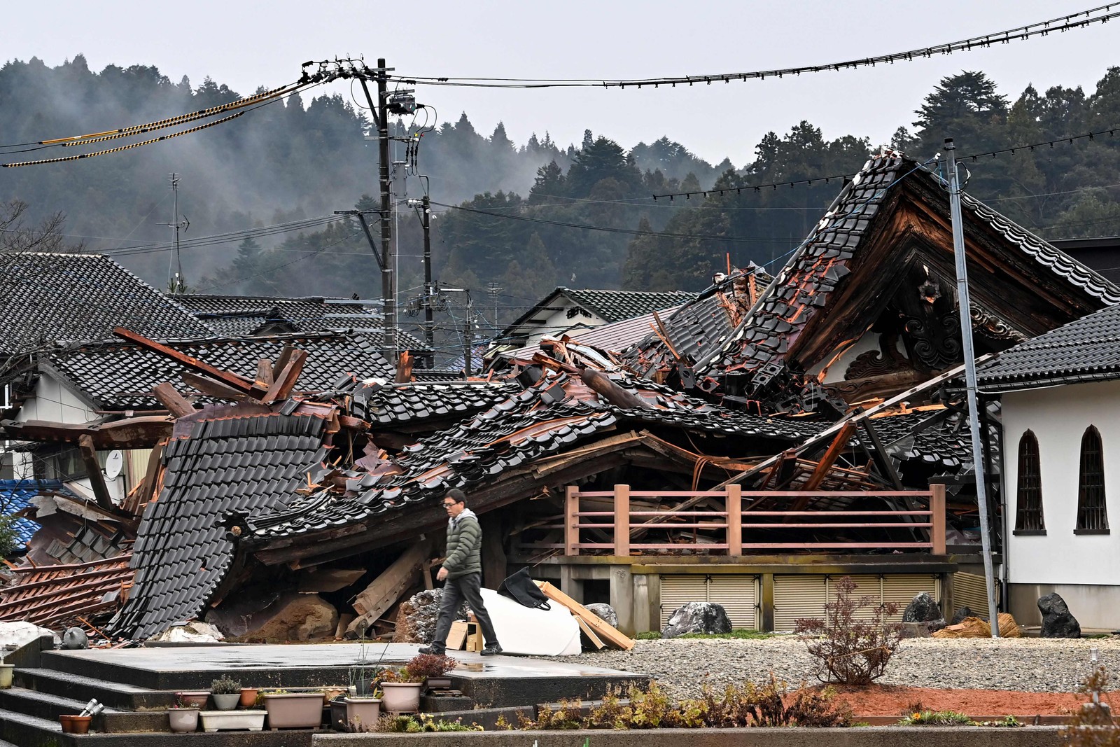 Homem caminha pelos escombros de casa destruída pelo terremoto no Japão — Foto: KAZUHIRO NOGI/AFP