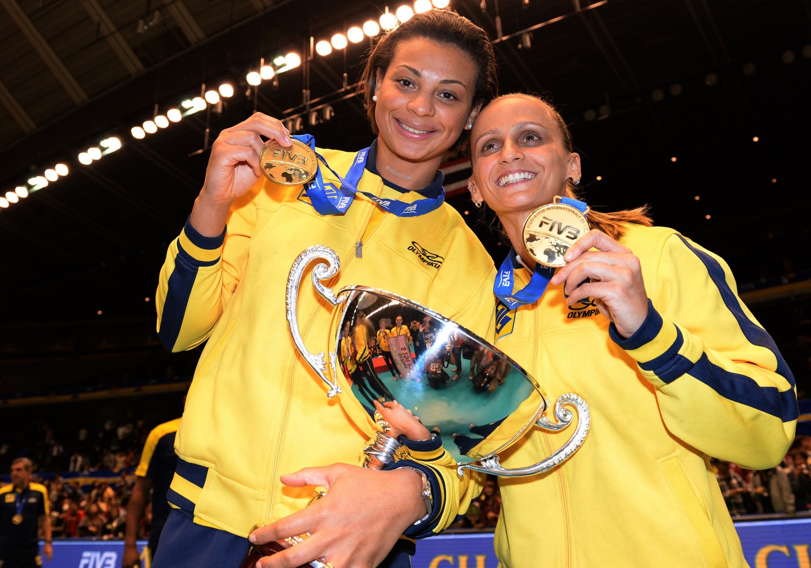 Walewska Oliveira (E) segura o troféu da vitória com Fabiana Oliveira (R) durante a cerimônia de premiação da Copa dos Grandes Campeões Femininos de vôlei da FIVB, em Tóquio em 2013 — Foto: TOSHIFUMI KITAMURA/AFP