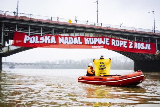 Faixa de ativistas do Greenpeace com os dizeres 'A Polônia ainda compra petróleo da Rússia' em uma ponte sobre o rio Vístula em Varsóvia