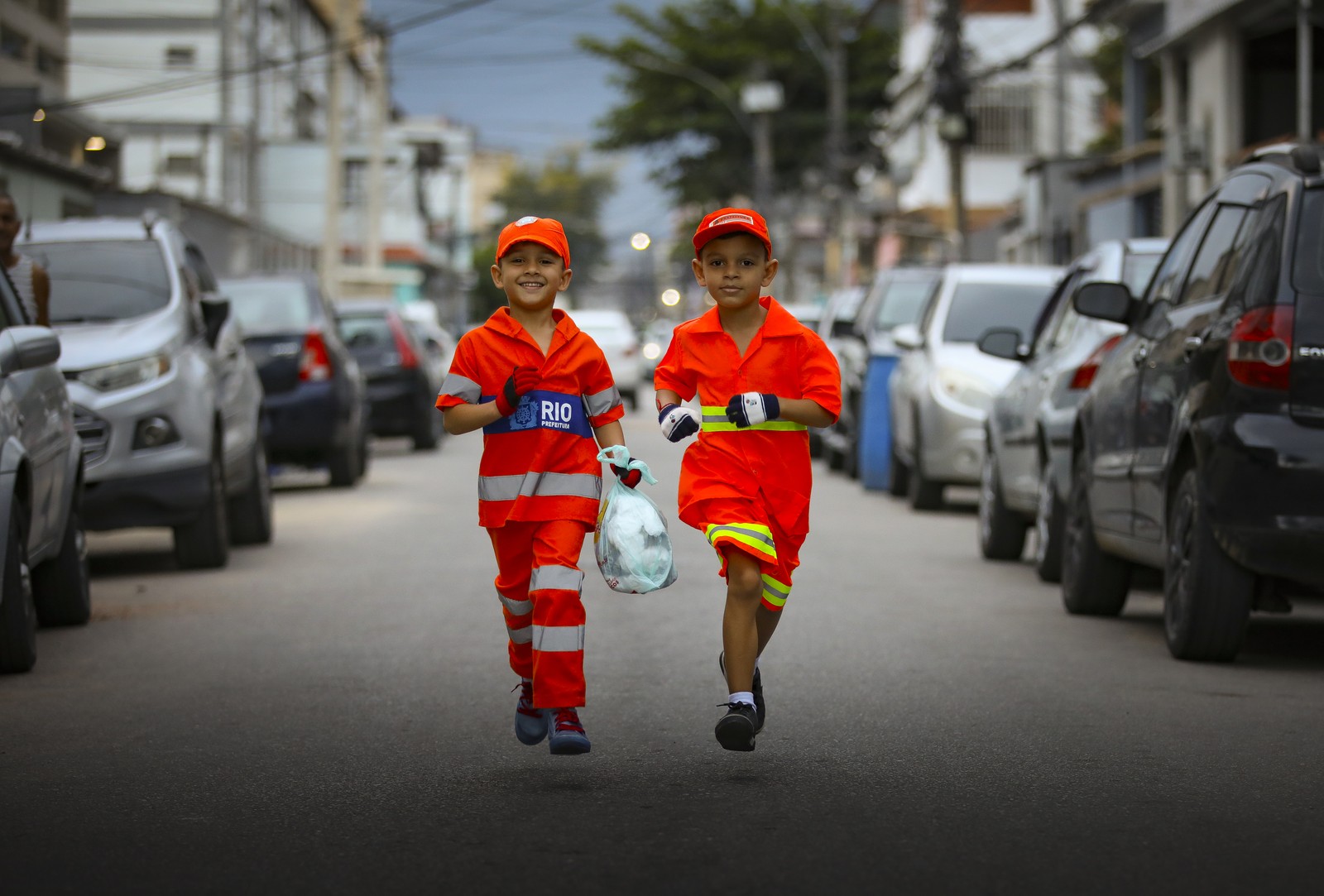 Os irmãos Bryan Mota, de 6 anos, e Bernardo Mota, de 7, ajudam garis a recolherem lixo nas ruas de Bangu — Foto: Lucas Tavares/ O GLOBO