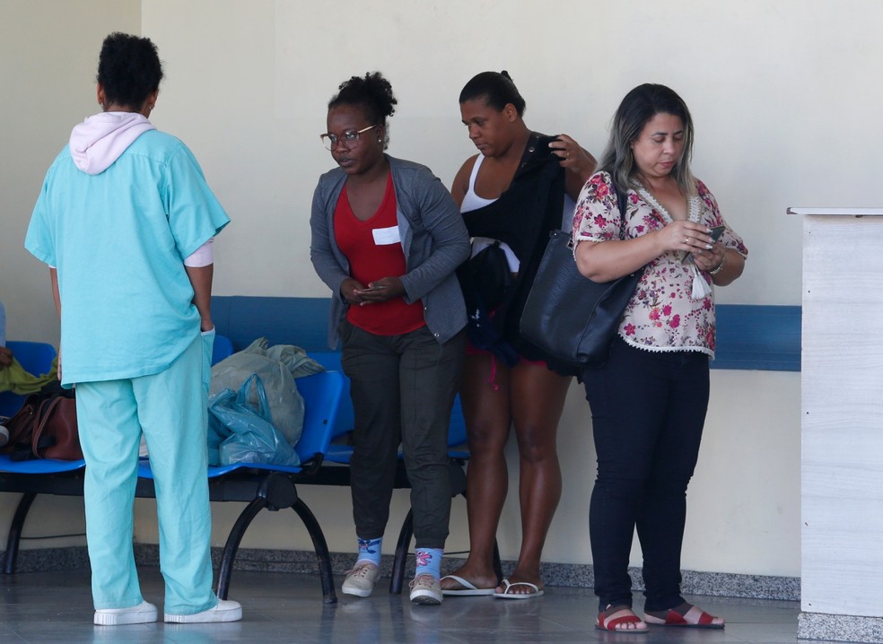 Parentes da menina conversam com um funcionário do Hospital Evandro Freire — Foto: Fabiano Rocha/Agência O Globo