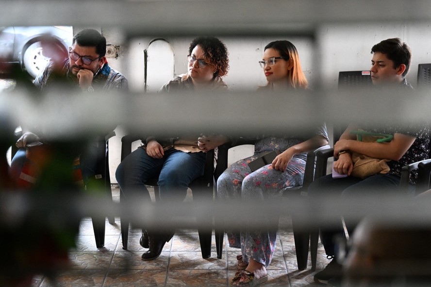 Fiorella Turchkeim (2ª esq.) e Andrea Ordoñez (2ª dir.) dão as mãos durante um culto em uma organização de inspiração anglicana, um dos poucos espaços abertos a devotos LGBTQIAP+ em San Salvador