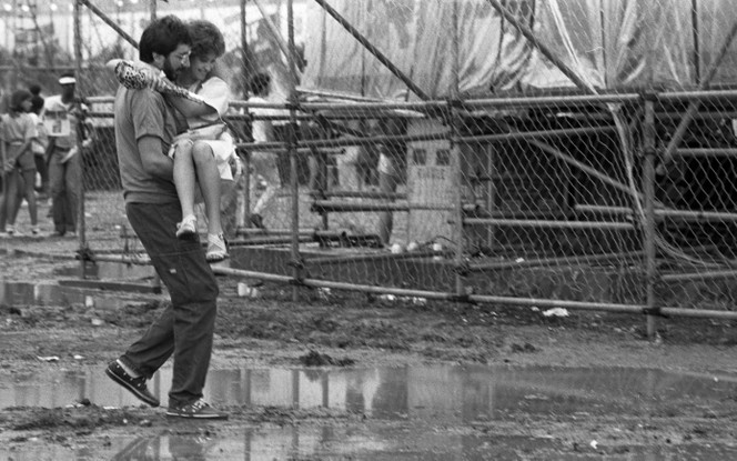 Rock in Rio: Homem carrega mulher sobre poças de lama, em 1985