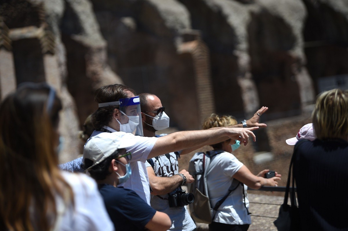 Guia e visitantes usando máscaras dentro do Coliseu no dia da reabertura do sítio históricoAFP