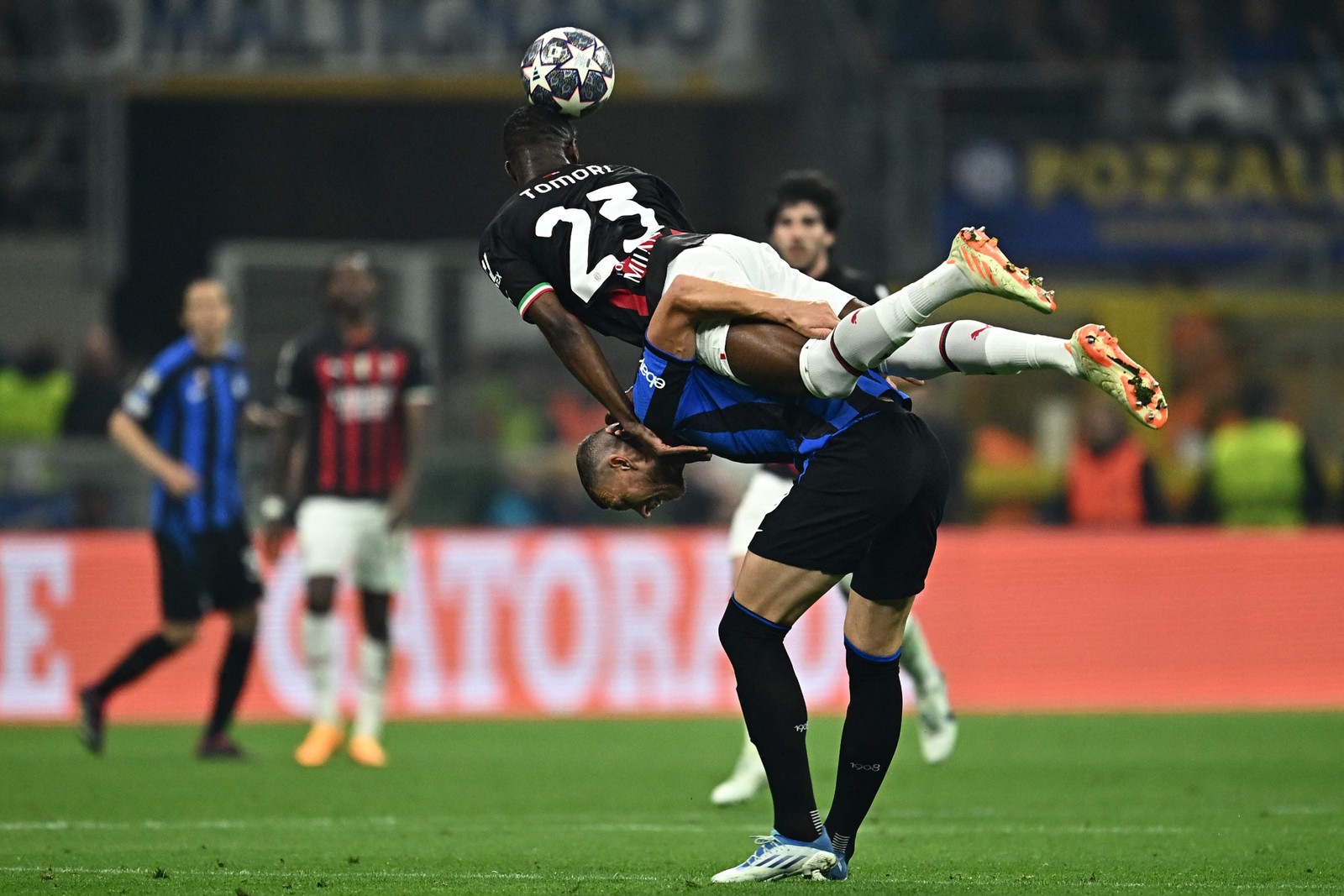 O zagueiro britânico do AC Milan, Fikayo Tomori, apoia-se nas costas do atacante bósnio do Inter de Milão, Edin Dzeko — Foto: GABRIEL BOUYS / AFP