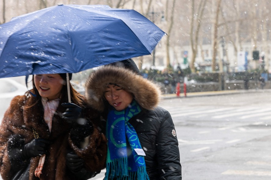 Mulheres tentam se proteger da neve e da temperatura negativa ao caminhar por Nova York