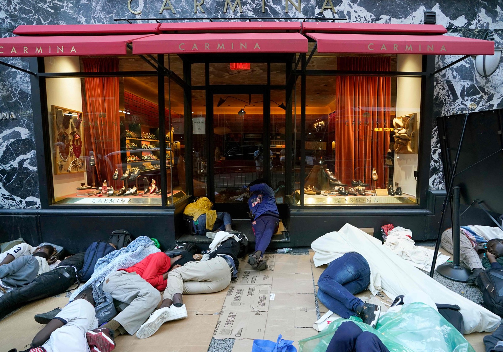 Imigrantes em busca de asilo dormem na calçada suja de Nova York, do lado de fora de um hotel em Manhattan — Foto: TIMOTHY A. CLARY / AFP