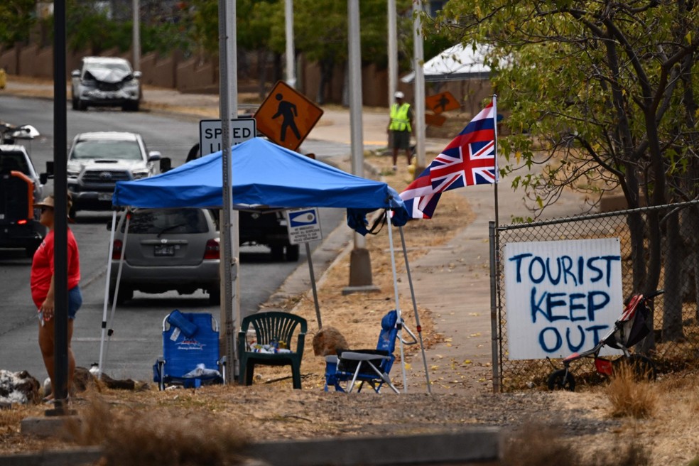 Placa pedindo que turistas se mantenham longe da região afetada pelos incêndios florestais em Mali, no Havaí. População do estado americano sofre com 'overtourism' há anos — Foto: Patrick T. Fallon / AFP