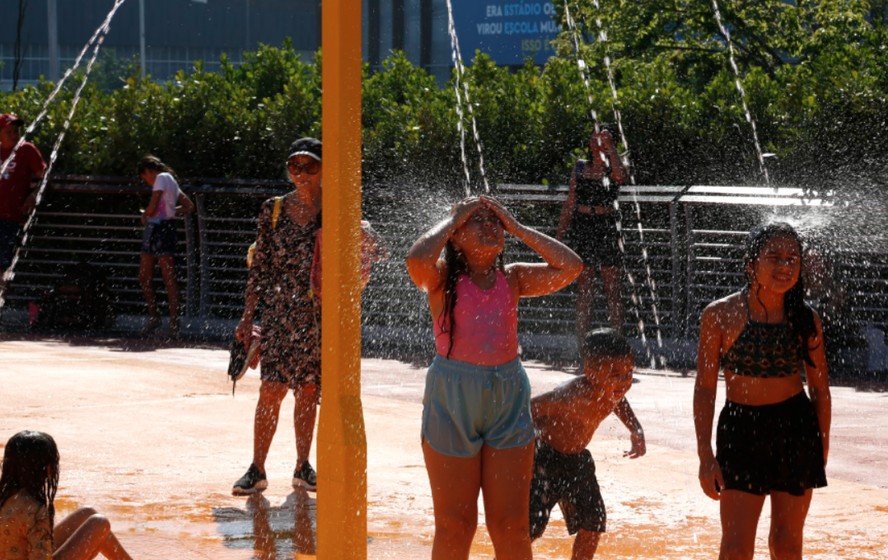 Crianças se refrescam e se divertem na praça molhada