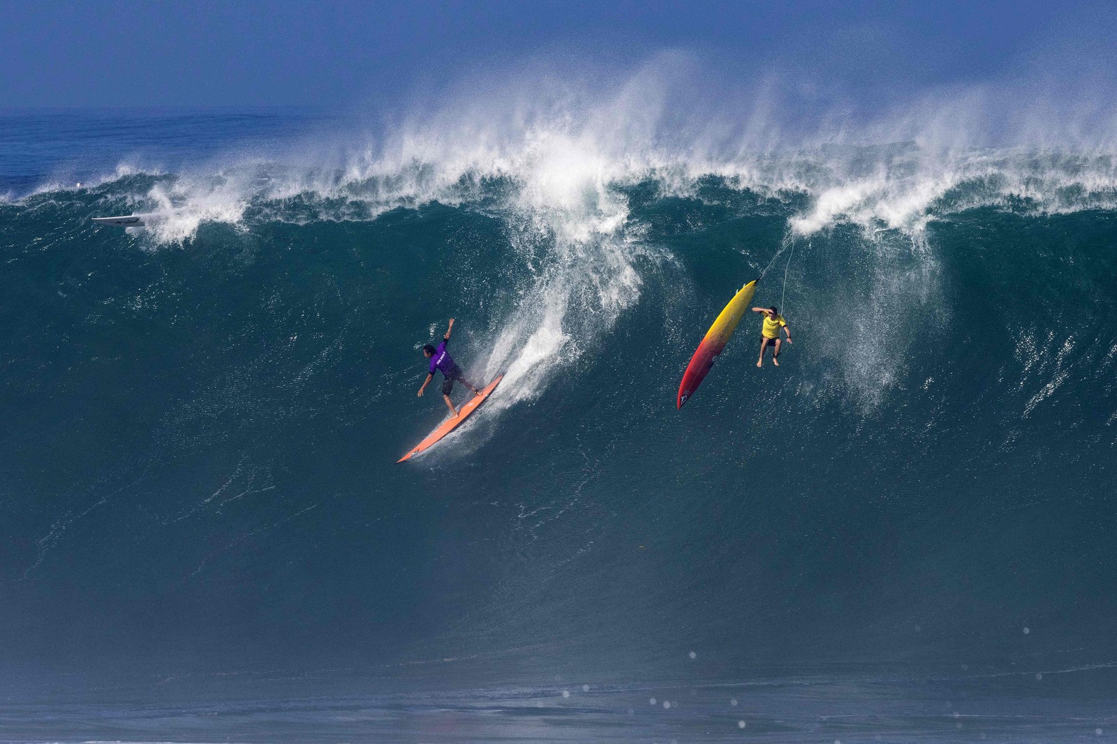 O surfista dos EUA Eli Olsen pega uma onda enquanto o surfista havaiano Jake Maki é eliminado durante competição no Havaí — Foto: BRIAN BIELMANN/AFP