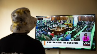 Mulher trans que foi recentemente atacada em Uganda assiste à transmissão da sessão do parlamento que aprovou o projeto de lei anti-LGBTQIA+ em 21 de março de 2023 — Foto: Stuart Tibaweswa / AFP