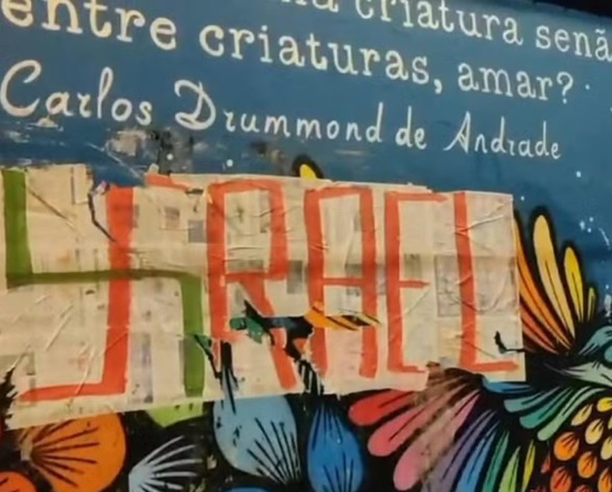 Cartaz com referência a Israel e símbolo nazista colado sobre mural em homenagem a Carlos Drummond de Andrade no Teatro Municipal Sérgio Porto, em janeiro
