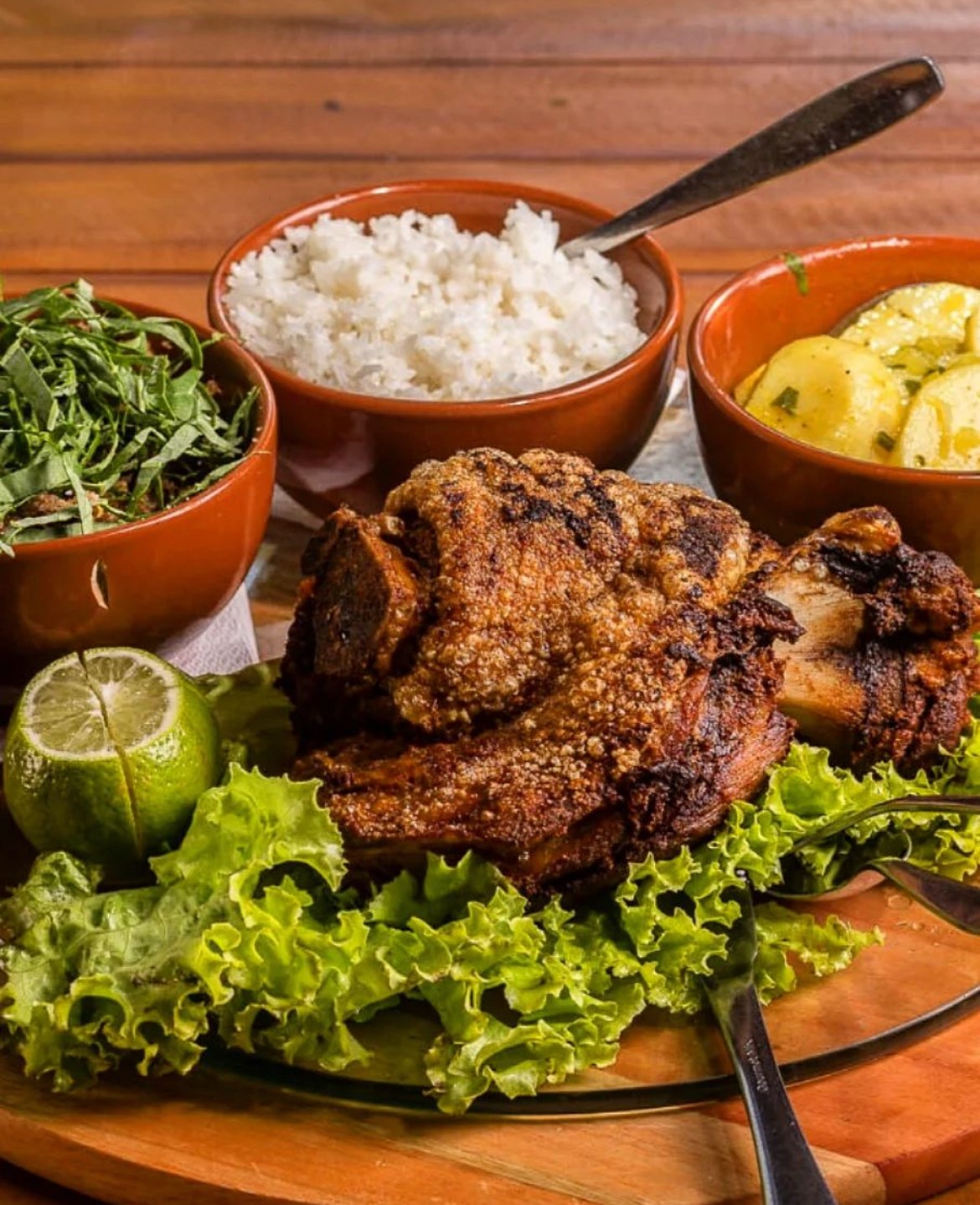 Uma das especialidades do Gugut Restaurante é o leitão pururuca, acompanhado de arroz, conserva de batatas e feijão tropeiro — Foto: Divulgação