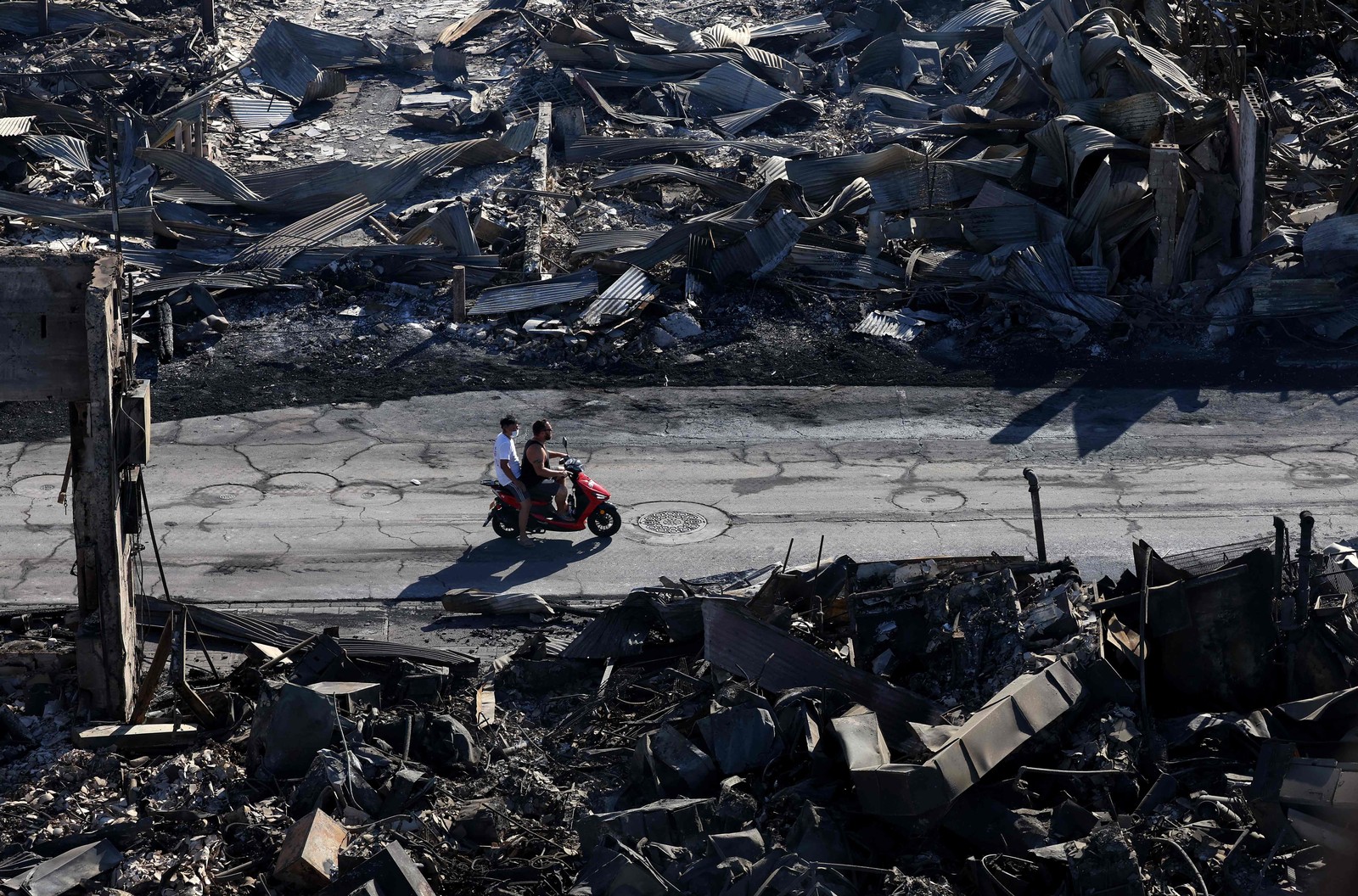 Em uma vista aérea, dois homens andam de scooter por empresas que foram destruídas por um incêndio florestal em 11 de agosto de 2023 em Lahaina, Havaí — Foto: Justin Sullivan / Getty Images via AFP