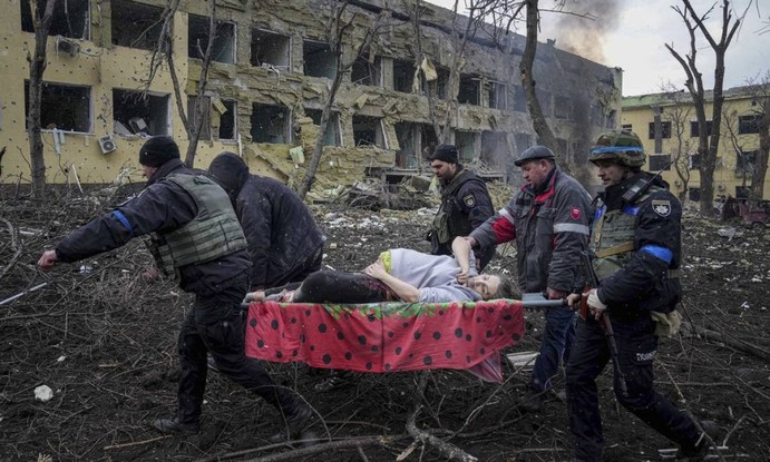 Funcionários e voluntários de emergência ucranianos carregam uma mulher grávida ferida da maternidade em Mariupol, na Ucrânia