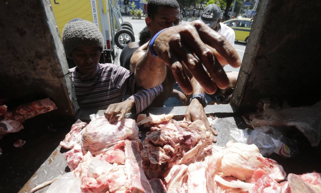 Fila da fome. Pessoas em situação de rua disputam restos de carne em caminhão.  — Foto: Domingos Peixoto / Agência O Globo