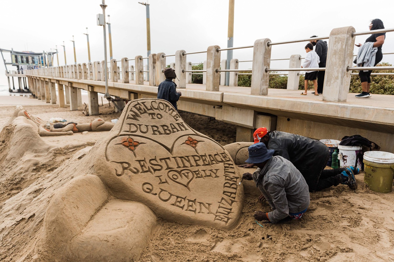 Escultor de areia sul-africano dá toques finais à mensagem em homenagem à Rainha Elisabeth II, na praia do Píer Moyo, em Durban — Foto: RAJESH JANTILAL / AFP