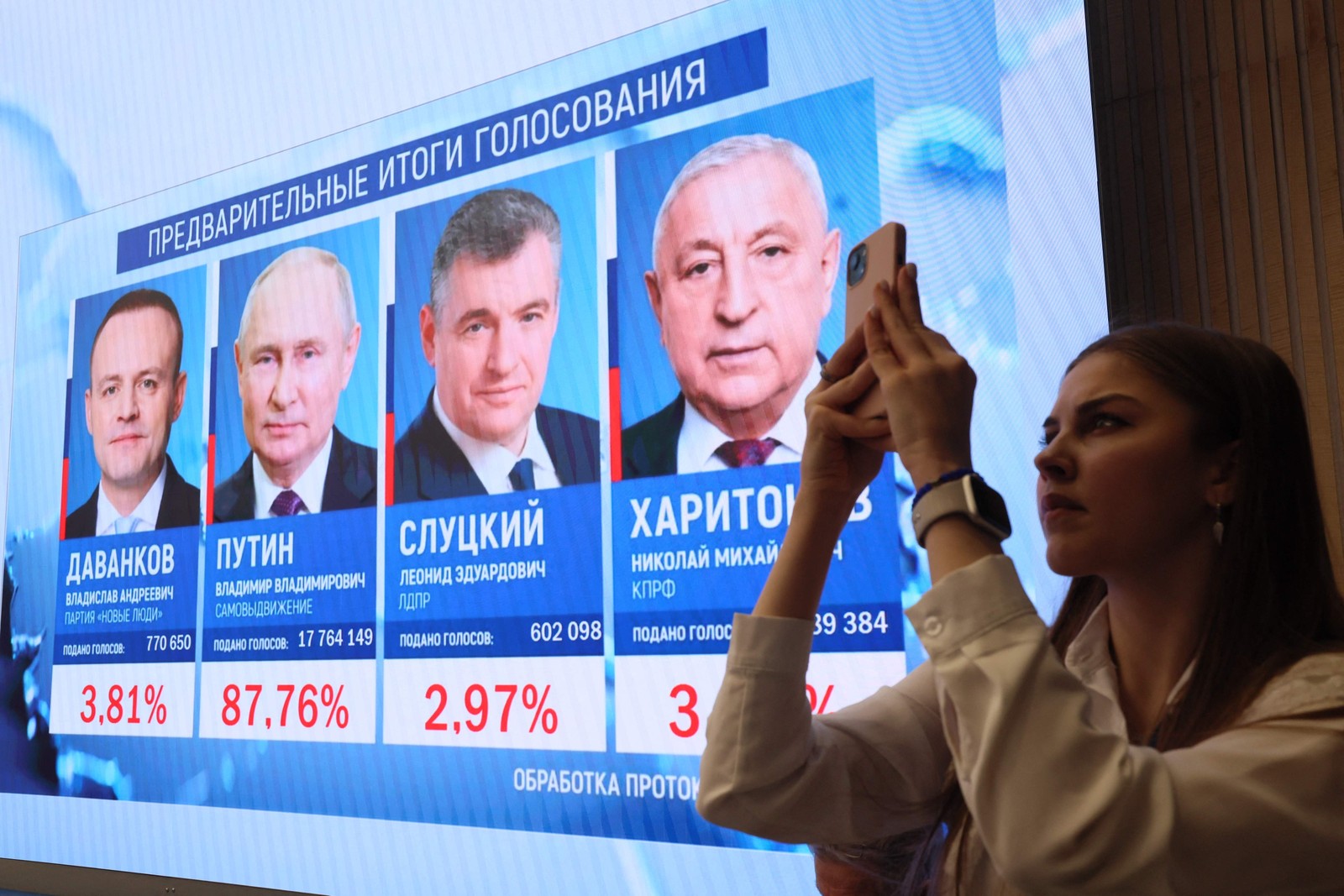 Mulher tira uma fotos diante de um painel com os resultados preliminares das eleições russas na Comissão Eleitoral Central em Moscovo — Foto: AFP
