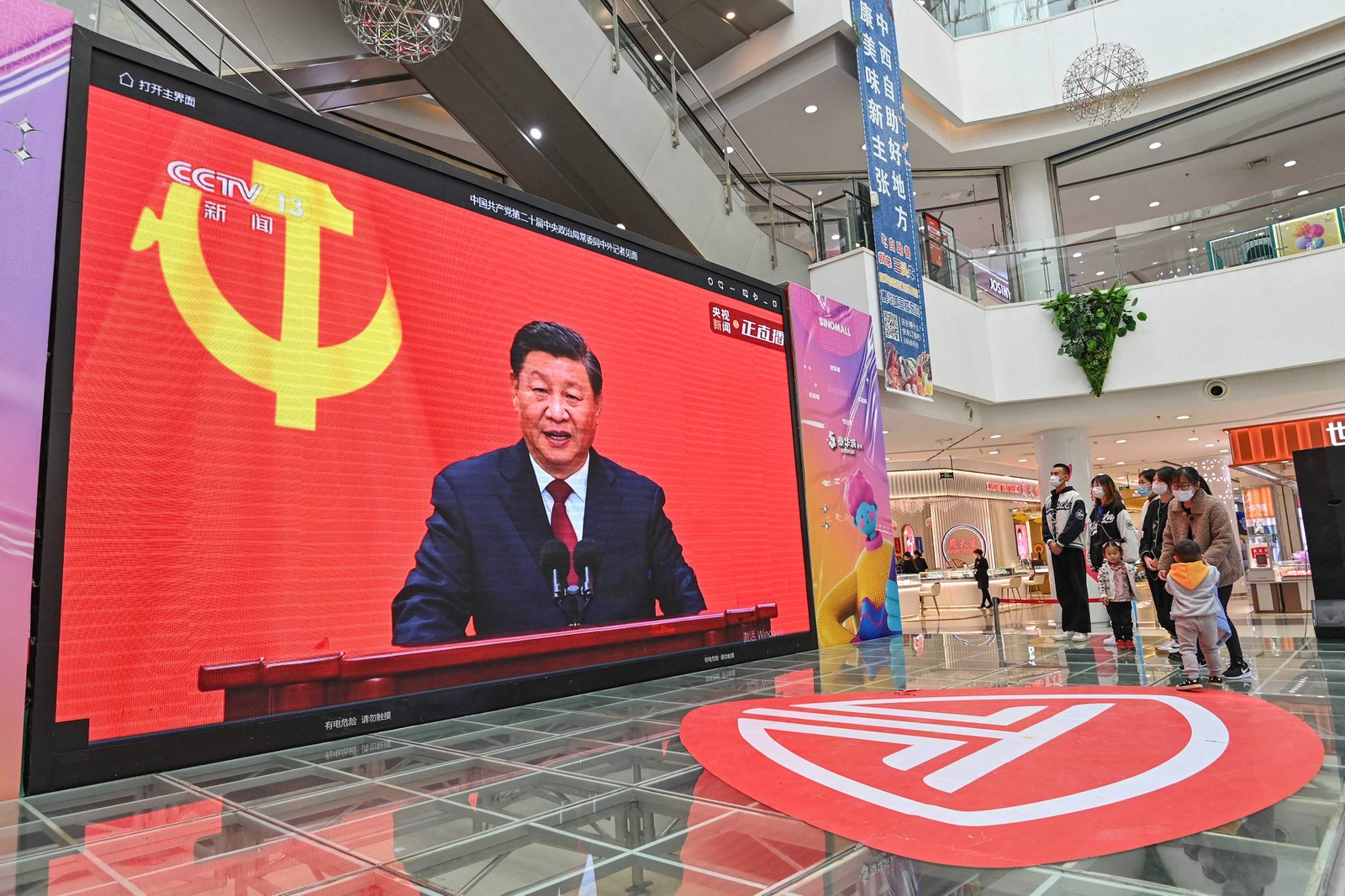 Pessoas assistem a uma transmissão ao vivo do presidente da China, Xi Jinping, falando durante a introdução do Comitê Permanente do Partido Comunista da China no Politburo — Foto: AFP
