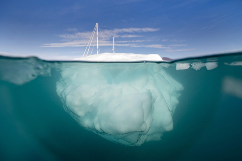 A ponta do iceberg. Detalhe do barco à vela 'Kamak' da expedição da Groenlândia navegando entre icebergs liberados por geleiras ao redor de Milne Land no fiorde Scoresby Sound, leste da Groenlândia — Foto: Olivier MORIN/AFP