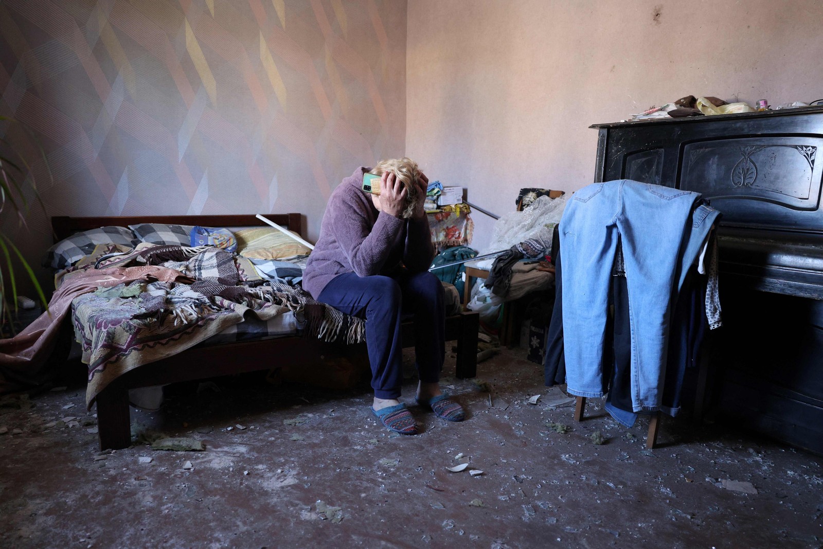 A moradora local Oksana, 54 anos, reage ao quarto de sua casa, que foi danificado por um ataque de mísseis na vila de Krasylivka, região de Kiev — Foto: Anatolii STEPANOV/AFP