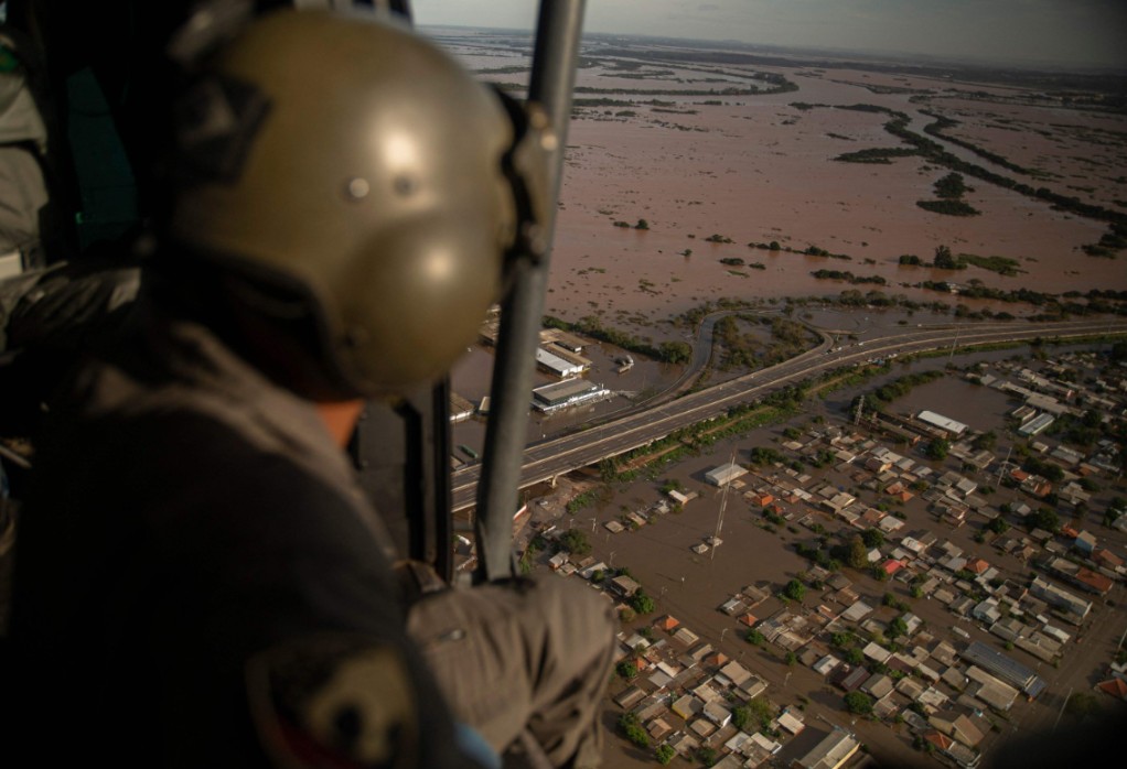 Militar sobrevoa de helicóptero as ruas alagadas de Porto Alegre — Foto: Carlos Fabal/AFP