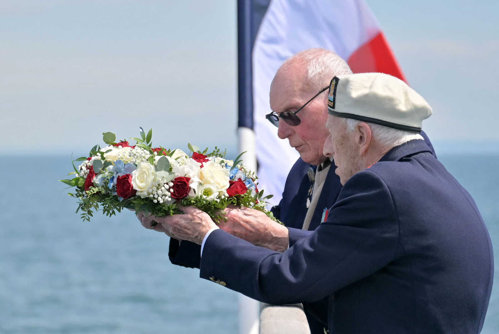 Veteranos britânicos se preparam para lançar uma homenagem floral ao mar do convés de uma balsa durante uma cerimônia na costa em Ouistreham, norte da França, em 4 de junho de 2024, como parte das comemorações do "Dia D" — Foto: Lou Benoist / AFP