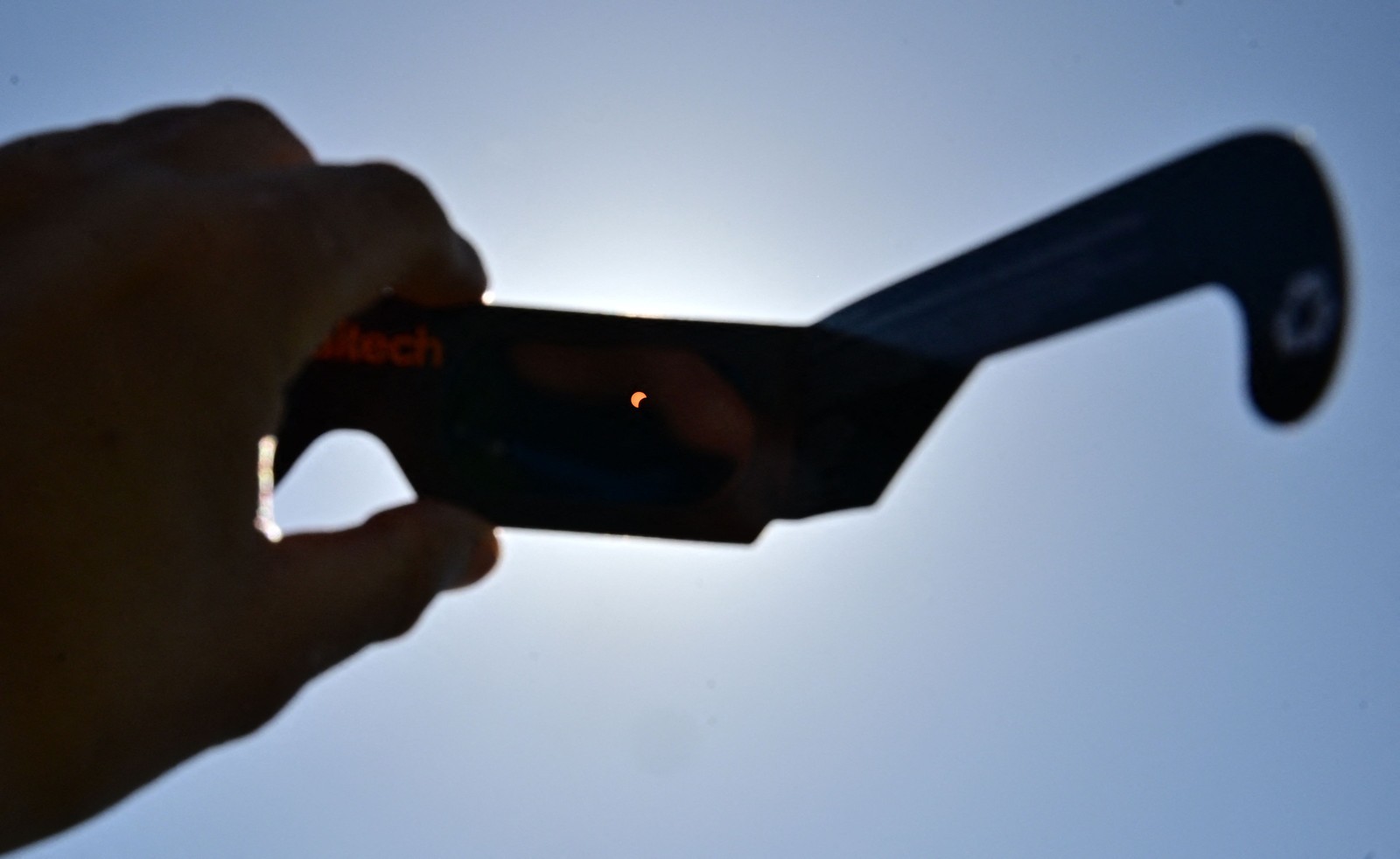 Visão do eclipse solar através de óculos de proteção dados às pessoas que se reuniram para o evento no Caltech em Pasadena, Califórnia. - Foto:  Frederic J. BROWN / AFP