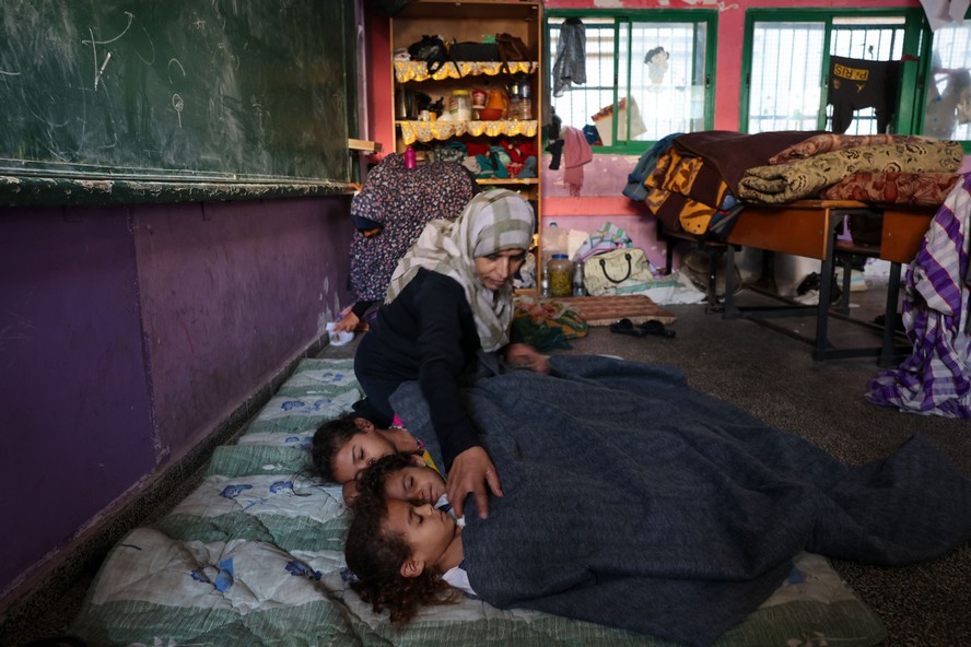 Mulher cobre crianças em campo de refugiados de Rafah, em Gaza