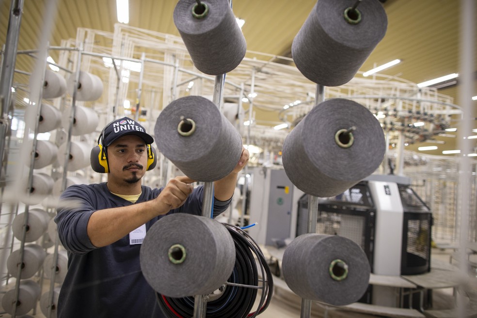 Nesta máquina, dezenas de novelos desenrolam os fios dando forma aos tecidos que depois serão lavados, tingidos, estampados e cortados Agência O Globo — Foto:         