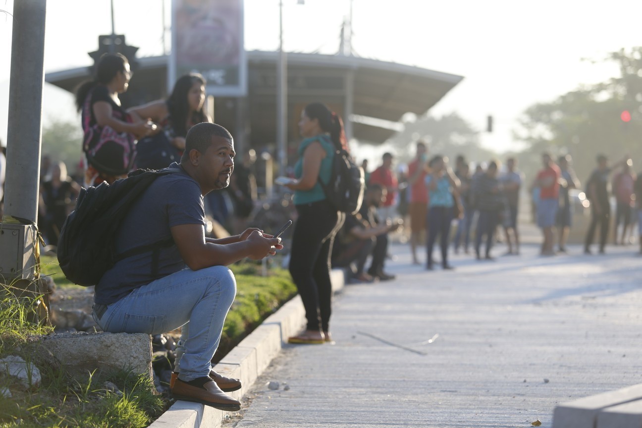 Passageiros na Estação Magarça, na Zona Oeste, um dia após os ataques que incendiaram ao menos 35 ônibus no Rio. Rodrigo Santos, sentado no meio fio. — Foto: Fabiano Rocha / Agência O Globo