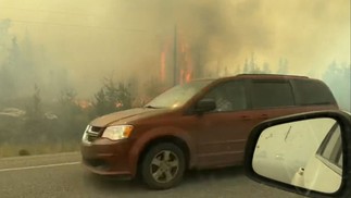 Imagem mostra veículos dirigindo na rodovia enquanto as pessoas figem de Yellowknife, no Canadá — Foto: Jordan Straker / UGC / AFP