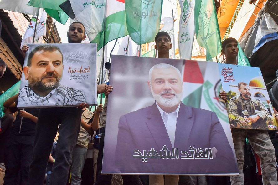 Manifestantes seguram fotos do líder do Hamas, Ismail Haniyeh (C), e do líder sênior Saleh al-Arouri durante protesto em Beirute; ambos foram mortos por ataques de Israel