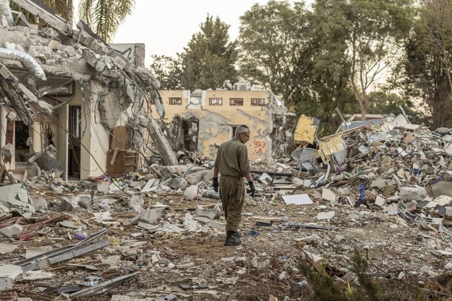 Soldado israelense procura por restos humanos em meio aos escombros deixados após o ataque do Hamas em 7 de outubro em Be'eri, um kibutz perto da fronteira com Gaza