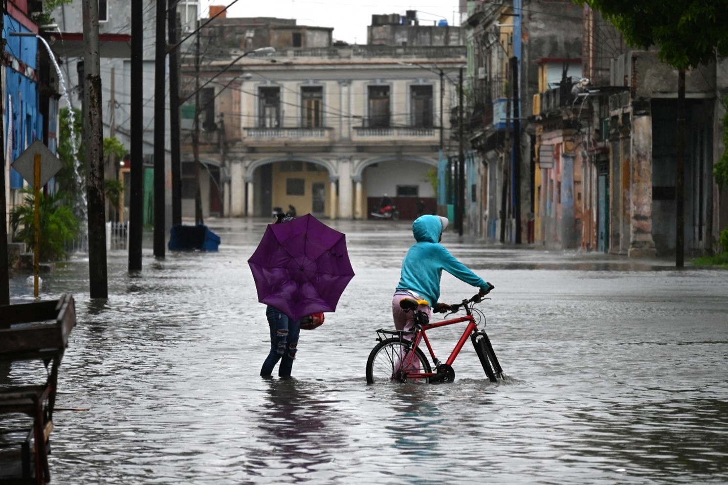 Pessoas caminham por uma rua inundada em Havana, durante a passagem da tempestade tropical Idalia. — Foto: Yamil LAGE/AFP