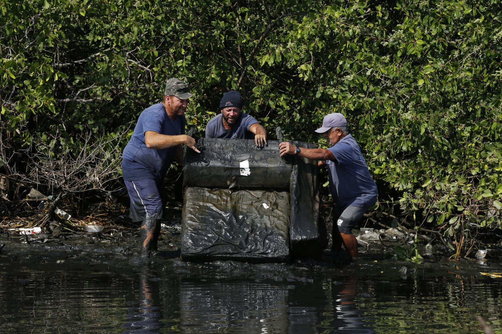 Pescadores retiram sofá de área de mangue na Ilha do Governador — Foto: Custodio Coimbra 