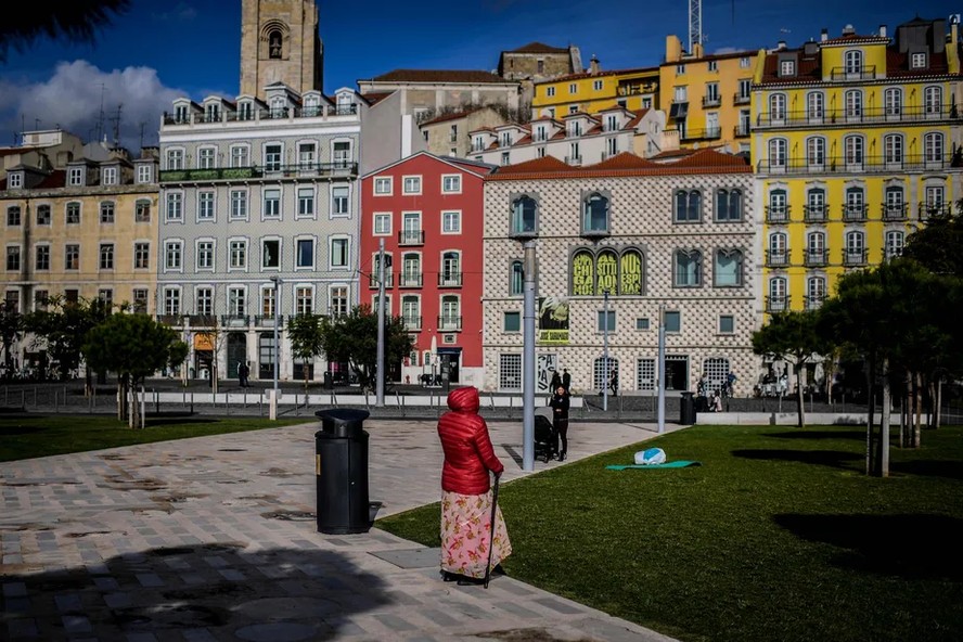 Mulher observa prédios em uma praça de Lisboa