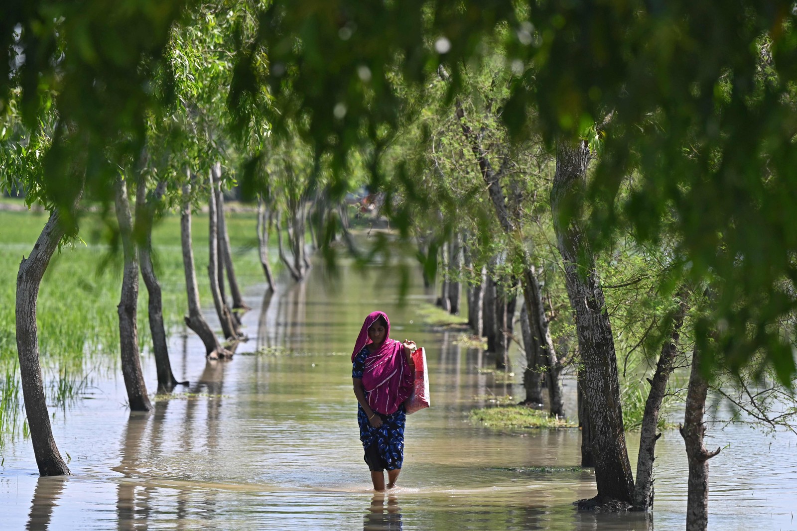 Mulher atravessa a maré entupida após o ciclone Sitrang atingir Kalapara, Bangladesh, onde centenas de milhares de pessoas foram evacuados de casa — Foto: MUNIR UZ ZAMAN/AFP