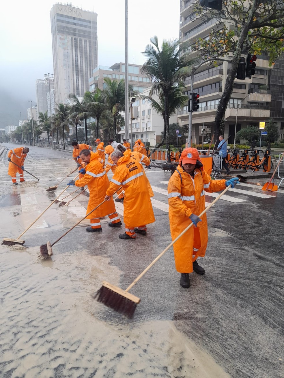 Garis limpam o trecho da praia do Leblon — Foto: Comlurb