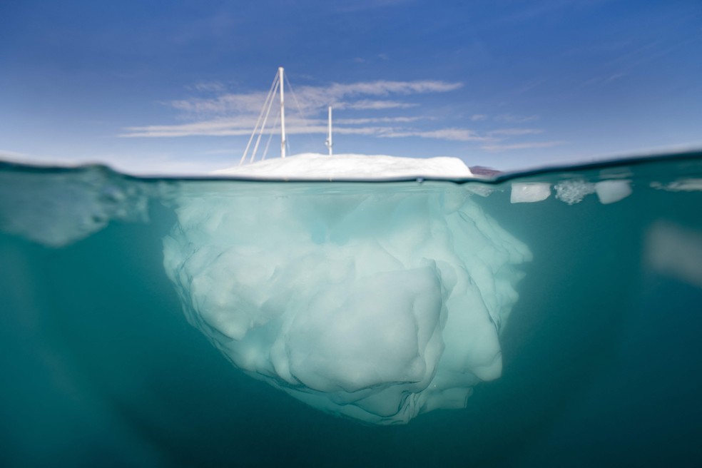 Um barco navega entre icebergs no Estreito de Scoresby, na Groenlândia, onde o degelo tem sido recorde — Foto: OLIVIER MORIN/AFP